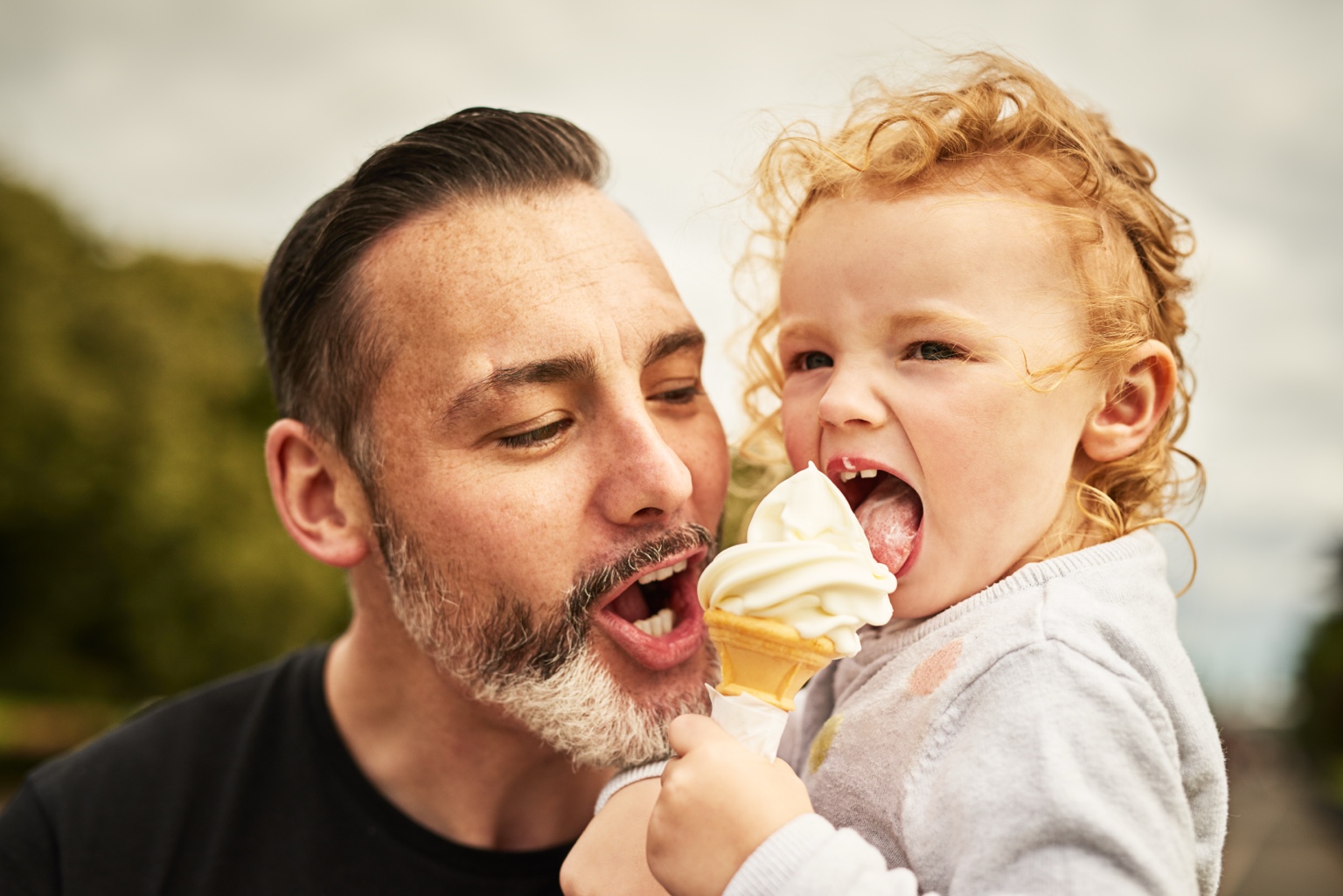 A father and young child sharing an ice cream cone