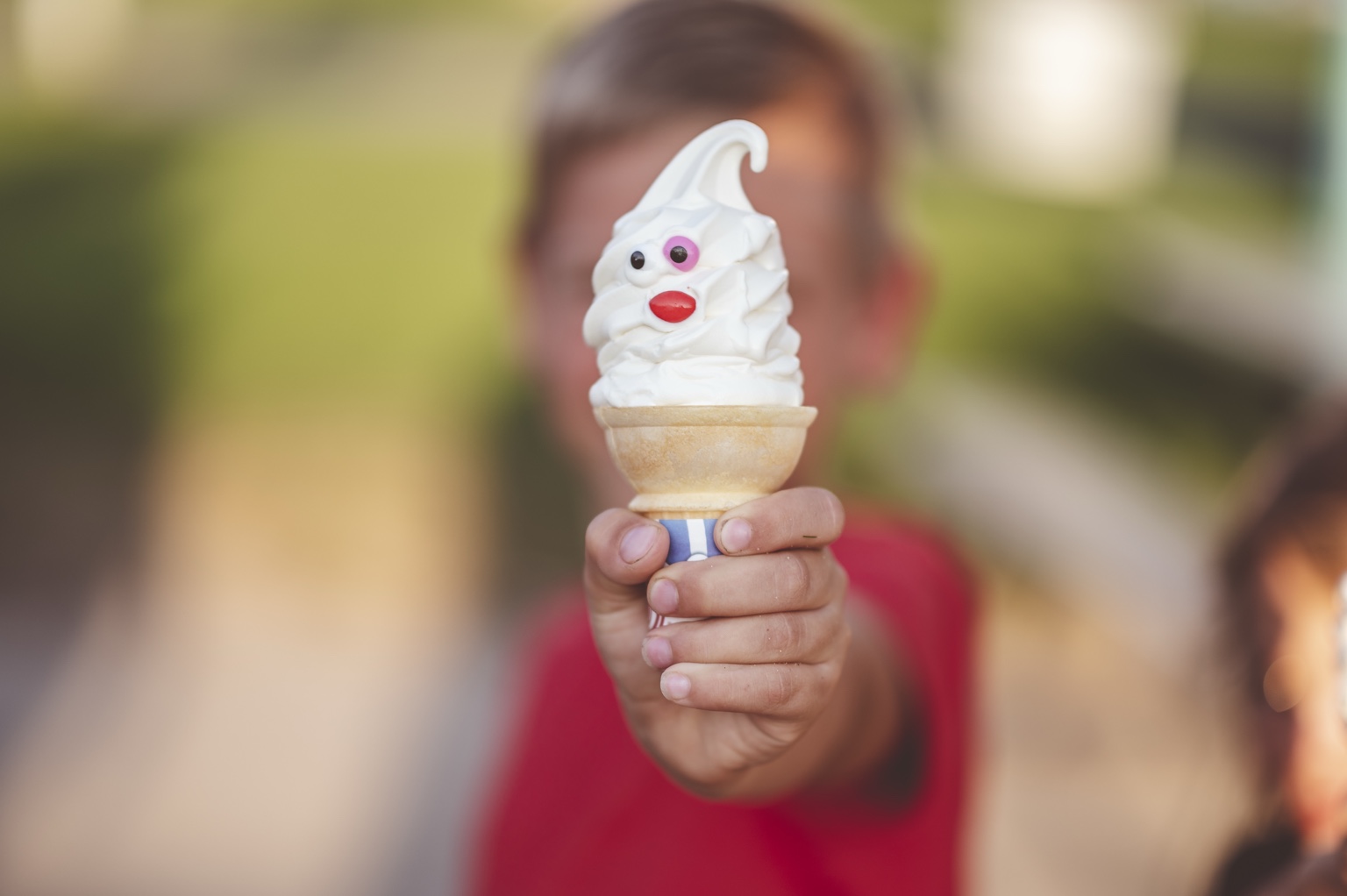 A child proudly holding a playful ice cream cone