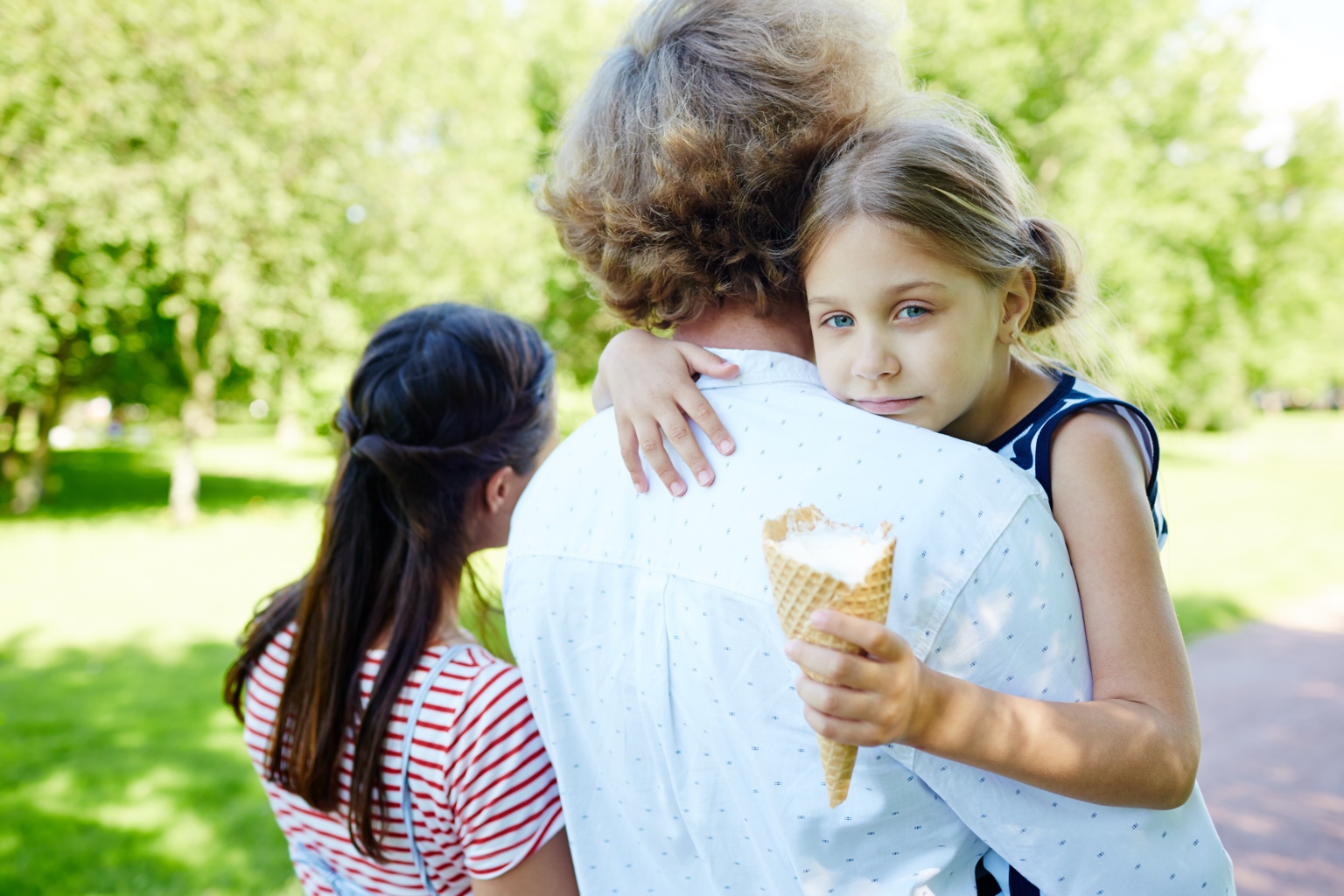 A child hugging a parent while holding an ice cream cone