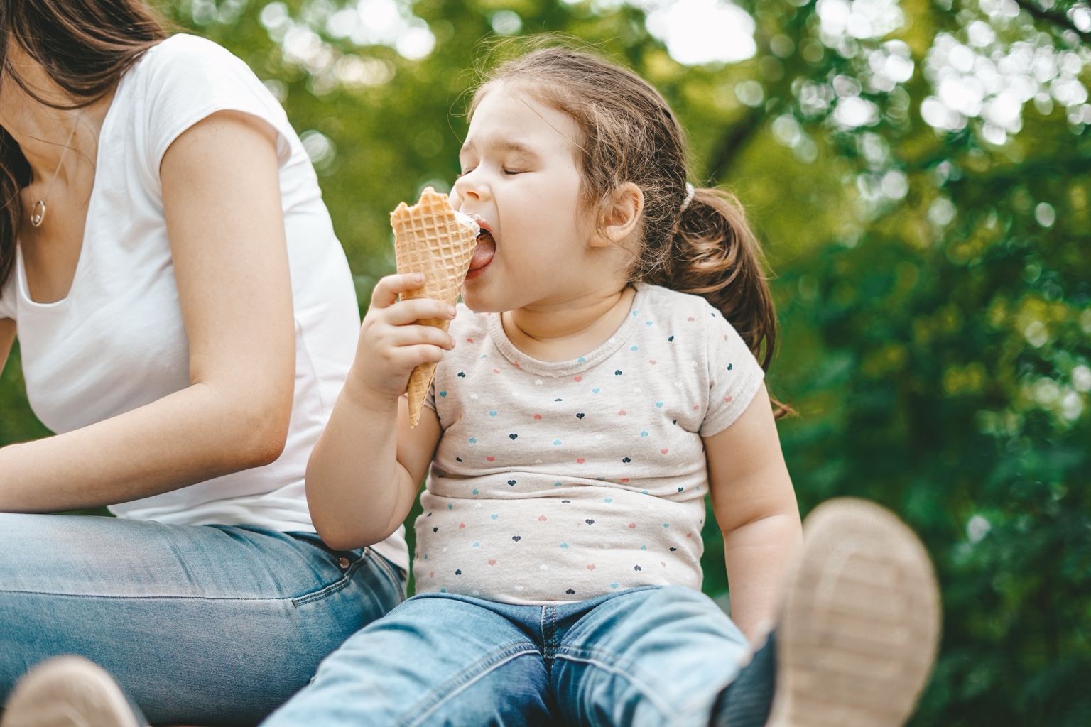A child enjoying ice cream with family in a green park